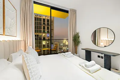 a bedroom with a white bed and a large window at Cozy 1 Bedroom in JVC with Stunning City Views in Dubai