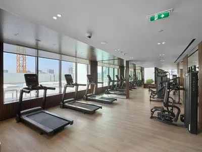 a gym with a row of treadms and elliptical machines at Cozy 1 Bedroom in JVC with Stunning City Views in Dubai