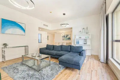 a living room with a blue couch and a glass table at Central JBR Home Steps away from the Beach in Dubai