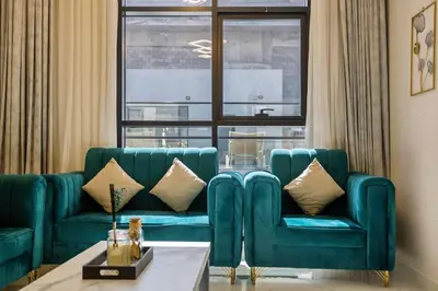 a living room with two blue couches and a window at 1BR Poolside Serenity in JVT in Dubai