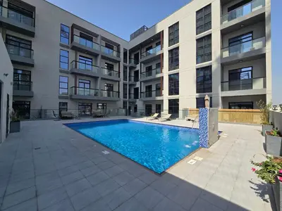 an apartment building with a swimming pool in a courtyard at 1BR Poolside Serenity in JVT in Dubai