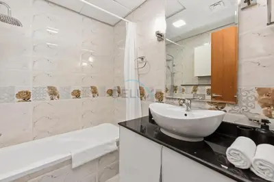 a white bathroom with a sink and a bath tub at High-Floor Studio, Walking Distance to the Park and 15-Min Drive to Miracle Garden, Al Jawhara Tower, Jumeirah Village Triangle by Deluxe Holiday Homes in Dubai