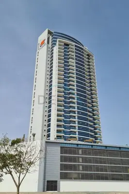 a tall building with a tree in front of it at High-Floor Studio, Walking Distance to the Park and 15-Min Drive to Miracle Garden, Al Jawhara Tower, Jumeirah Village Triangle by Deluxe Holiday Homes in Dubai