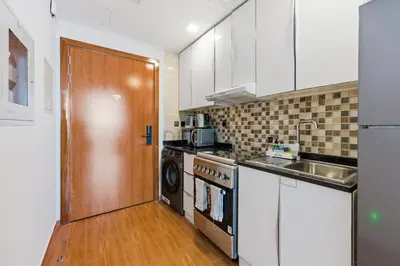 a kitchen with a sink and a washer and dryer at High-Floor Studio, Walking Distance to the Park and 15-Min Drive to Miracle Garden, Al Jawhara Tower, Jumeirah Village Triangle by Deluxe Holiday Homes in Dubai