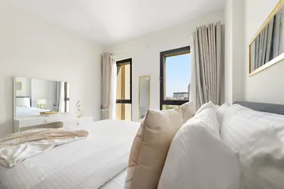 a white bedroom with a bed and a window at Luxury 1BR in Madinat Jumeirah Living in Dubai