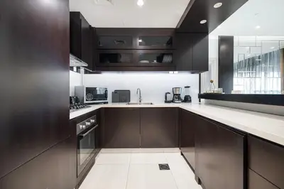 a kitchen with dark brown cabinets and white counter tops at Elegant 1-Bedroom Apartment at Downtown Dubai with Stunning Canal & Skyline Views in Dubai