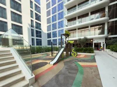 a playground in front of a building with a slide at Elegant Studio Escape in JVC - by Czechin in Dubai