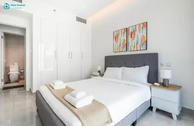 a bedroom with a large white bed and a bathroom at Blue Breeze Modern 2BR Apartment Near Downtown in Dubai