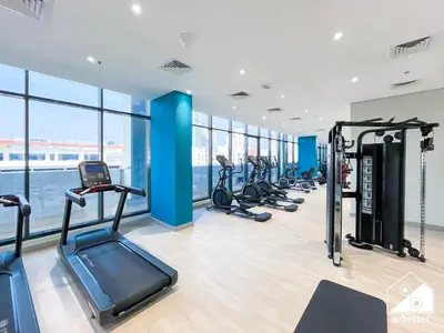 a gym with a row of treadmills and ellipticals at Premium Riviera Studio King Bed, Pool & Gym in Dubai