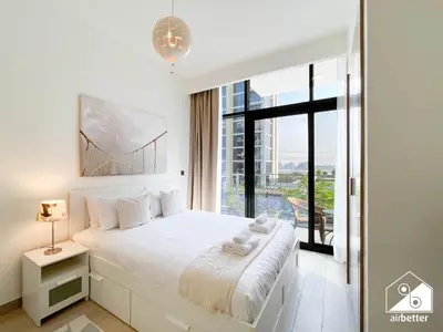 a white bedroom with a large bed and a window at Premium Riviera Studio King Bed, Pool & Gym in Dubai