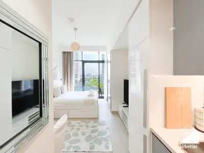 a white living room with a television and a bedroom at Bright City ST with Balcony l Pool, Gym & Wi-Fi in Dubai