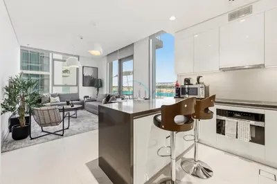 a kitchen and living room with white walls and windows at Lagoon-Facing 1BR, Minutes from Downtown and Business Bay, Near Dubai Water Canal - District One Phase III Residences 18 by Deluxe Holiday Homes in Dubai