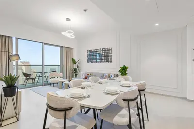 a white dining room with a table and chairs at Skyline Splendor 2bedroom with Burj Khalifa View in Dubai