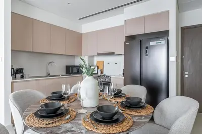 a kitchen with a table with chairs and a refrigerator at GuestReady - 2BR l High-Rise Elegance in Dubai