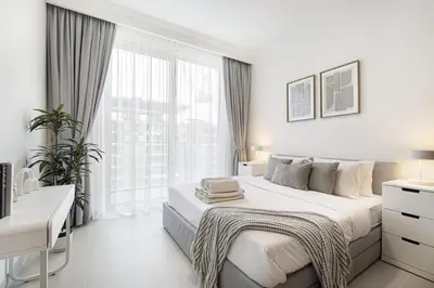 a white bedroom with a bed and a window at Beachfront 1BR with Private Beach Access in Dubai