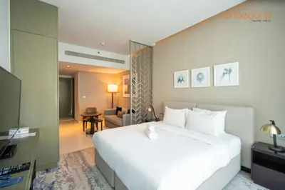 a bedroom with a large white bed and a living room at Modern Canal Studio near Downtown Dubai in Dubai