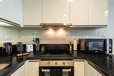 a kitchen with white cabinets and a stove top oven at Best Business Bay Location - Direct Views of Canal and Al Khail Racecourse - 1 min from Al Habtoor Palace in Dubai
