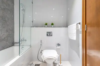 a white bathroom with a toilet and a shower at Best Business Bay Location - Direct Views of Canal and Al Khail Racecourse - 1 min from Al Habtoor Palace in Dubai