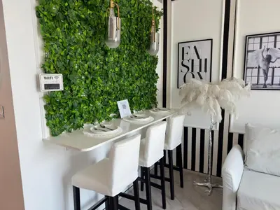 a dining room with a green wall and white chairs at JBR Beach Access Luxury1BR Marina View High Floor in Dubai