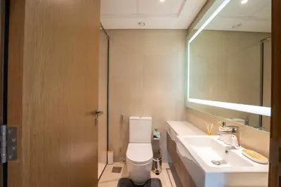a bathroom with a toilet and a sink and a mirror at EasyGo - Chic 2-Bedroom with Dubai Skyline View in Dubai