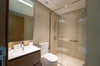 a bathroom with a shower and a toilet and a sink at EasyGo - Chic 2-Bedroom with Dubai Skyline View in Dubai