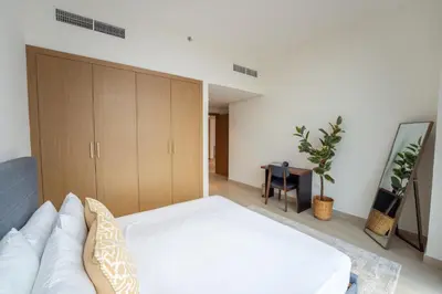 a bedroom with a white bed and wooden cabinets at EasyGo - Chic 2-Bedroom with Dubai Skyline View in Dubai