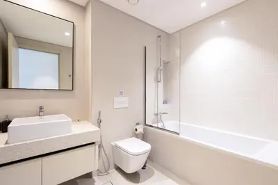a bathroom with a sink and a toilet and a mirror at Bright 1BR Walk to Beach Marina Vista Dubai in Dubai