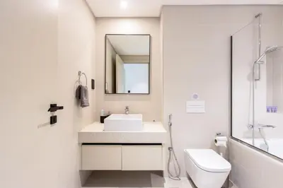 a bathroom with a sink and a toilet and a mirror at Bright 1BR Walk to Beach Marina Vista Dubai in Dubai