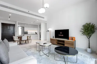 a living room with a couch and a tv at Bright 1BR Walk to Beach Marina Vista Dubai in Dubai