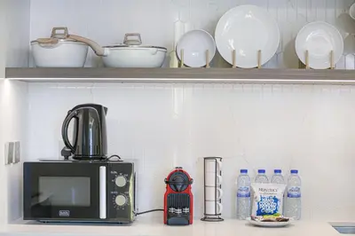 a kitchen counter with a microwave and plates and bottles of water at Palace Beach Residences By Luxe Living - Palm & Marina View in Dubai