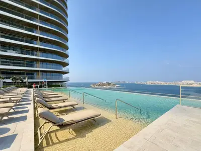 a row of chaise lounge chairs next to the ocean at Vogue Emaar Beachfront Grand Bleu Designed by Elie Saab, near JBR and Palm Jumeirah, Two Bedroom Apartment with Balcony and Private Beach, Access to all Amenities in Dubai