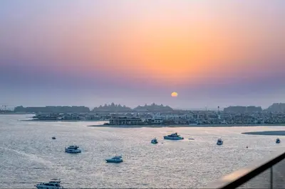 a group of boats in the water at sunset at Vogue Emaar Beachfront Grand Bleu Designed by Elie Saab, near JBR and Palm Jumeirah, Two Bedroom Apartment with Balcony and Private Beach, Access to all Amenities in Dubai