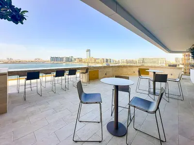 a rooftop patio with tables and chairs on a building at Vogue Emaar Beachfront Grand Bleu Designed by Elie Saab, near JBR and Palm Jumeirah, Two Bedroom Apartment with Balcony and Private Beach, Access to all Amenities in Dubai