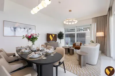 a living room with a table and chairs in a room at Vogue Emaar Beachfront Grand Bleu Designed by Elie Saab, near JBR and Palm Jumeirah, Two Bedroom Apartment with Balcony and Private Beach, Access to all Amenities in Dubai