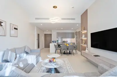a living room with a couch and a tv and a table at 1BR in GRANDE with Balcony I Amazing INFINITY POOL I Steps to Dubai Mall & Fountain in Dubai