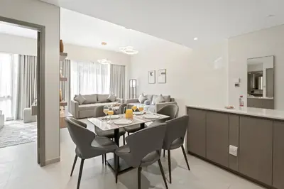 a dining room and living room with a table and chairs at 1BR in GRANDE with Balcony I Amazing INFINITY POOL I Steps to Dubai Mall & Fountain in Dubai