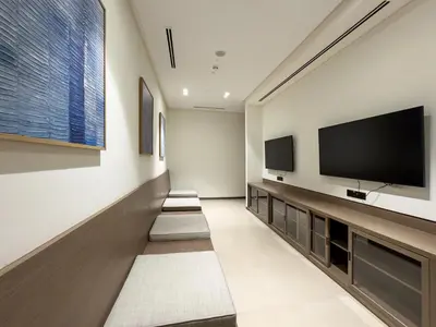 a living room with a flat screen tv and three benches at 1BR in GRANDE with Balcony I Amazing INFINITY POOL I Steps to Dubai Mall & Fountain in Dubai