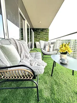 a patio with two chairs and a table on the grass at Luxury 2BR with Dubai Canal View Near Burj Khalifa in Dubai