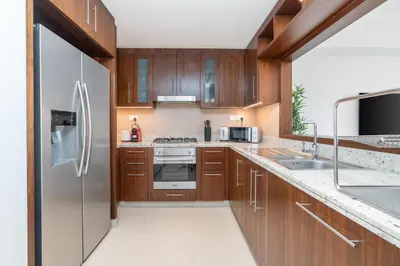 a kitchen with wooden cabinets and a stainless steel refrigerator at Boulevard Point I Burj Khalifa Fireworks View in Dubai