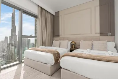 two beds in a room with a large window at King 2 Bedroom With Burj Khalifa View & Dubai Mall Access in Dubai