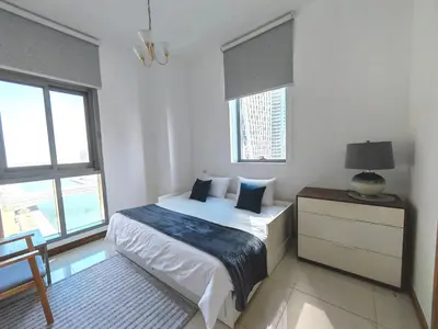 a white bedroom with a bed and two windows at Two Bedroom apartment - Dubai Marina in Dubai