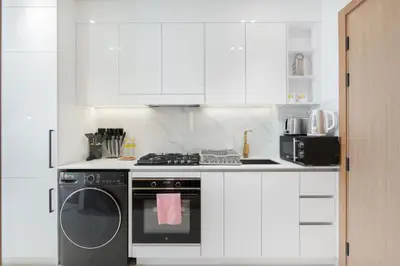 a white kitchen with a stove and a dishwasher at StayShort - Stylish Boho Studio in JVC Dubai Staycation Sleeps 2 in Dubai
