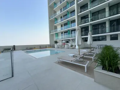 a large building with a pool and chairs and umbrellas at StayShort - Stylish Boho Studio in JVC Dubai Staycation Sleeps 2 in Dubai