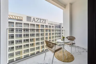 a balcony with a table and chairs and a building at Cozy & Modern Studio Stay in Azizi Riviera Meydan in Dubai