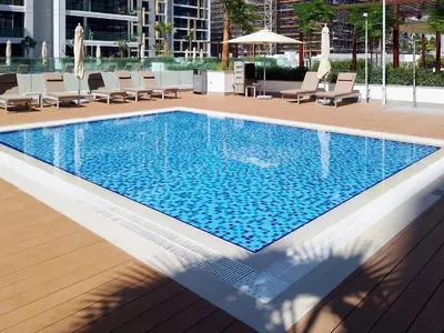 a swimming pool in a hotel with lounge chairs at Cozy & Modern Studio Stay in Azizi Riviera Meydan in Dubai