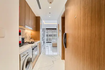 a kitchen with wooden cabinets and a washer and dryer at Cozy & Modern Studio Stay in Azizi Riviera Meydan in Dubai