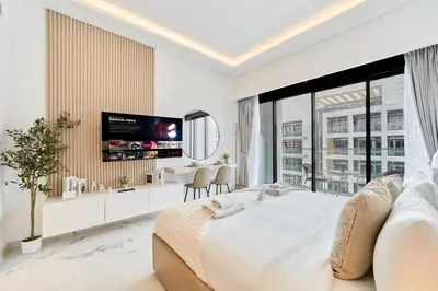 a white bedroom with a large bed and a flat screen tv at Cozy & Modern Studio Stay in Azizi Riviera Meydan in Dubai