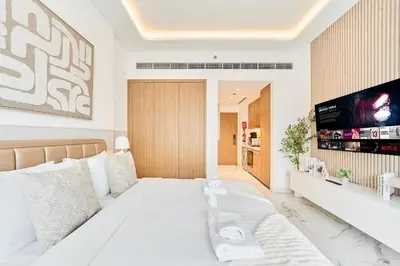 a bedroom with a large white bed and a flat screen tv at Cozy & Modern Studio Stay in Azizi Riviera Meydan in Dubai