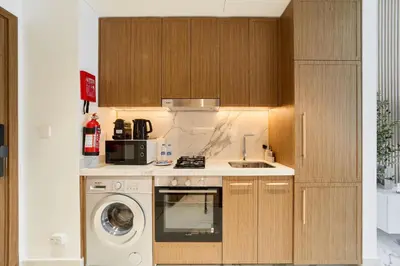 a kitchen with a washing machine and a washer at Cozy & Modern Studio Stay in Azizi Riviera Meydan in Dubai