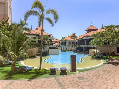 a resort swimming pool with lounge chairs and palm trees at Sea View 1BR - Private Beach Access Anantara in Dubai